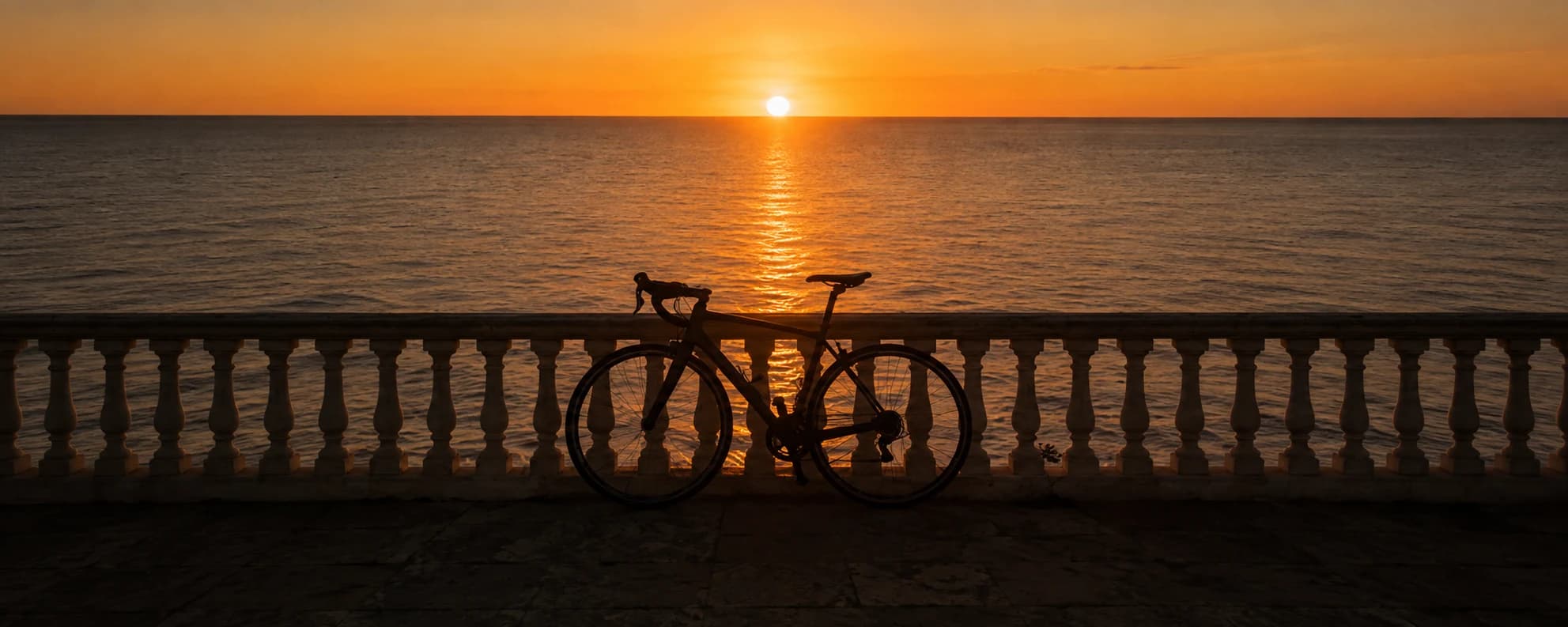 A road bike against a sea sunset, the sun low over the water